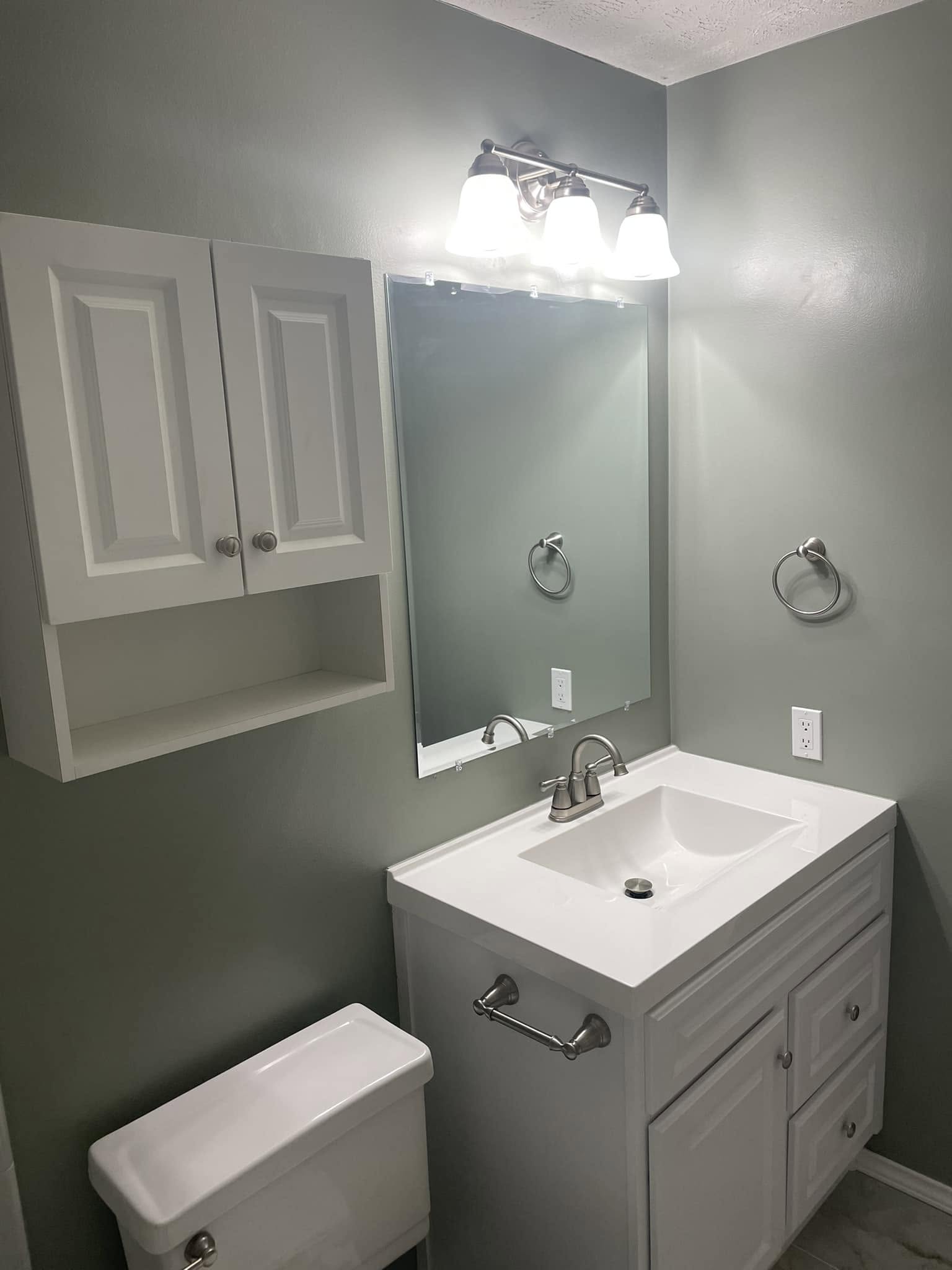 Guest bathroom refresh with white vanity, brushed-nickel fixtures, and sage walls in a McKinney home