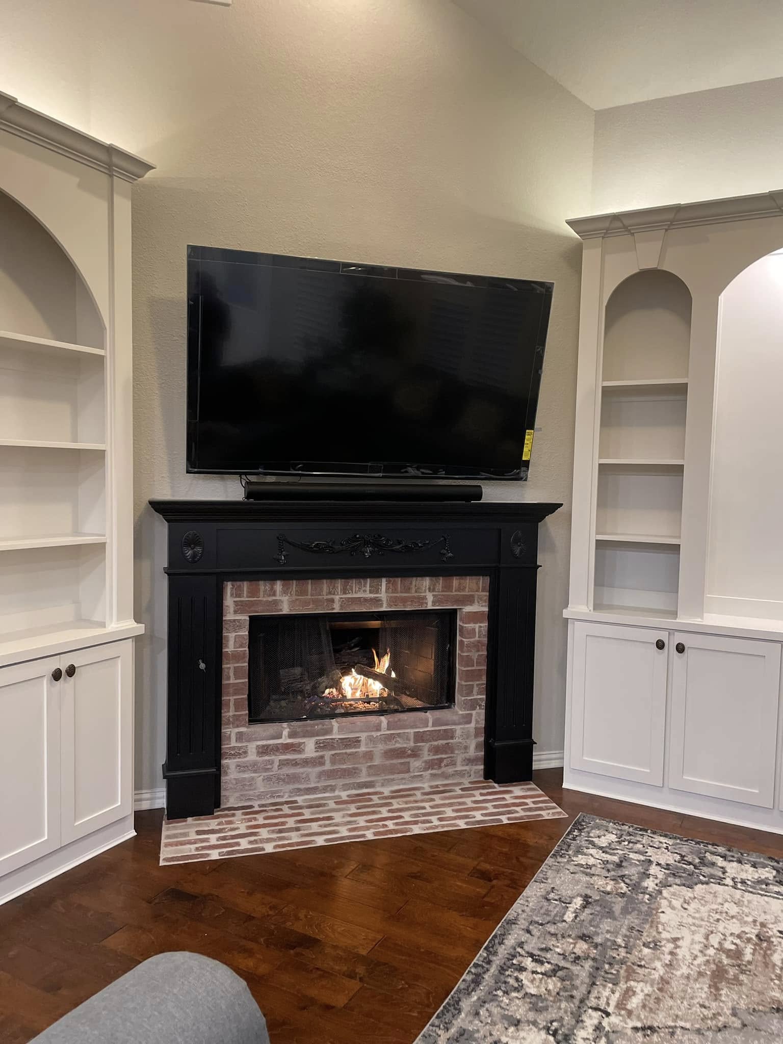 Custom arched built-in shelving flanking a brick fireplace, painted finish carpentry by Andrades GC