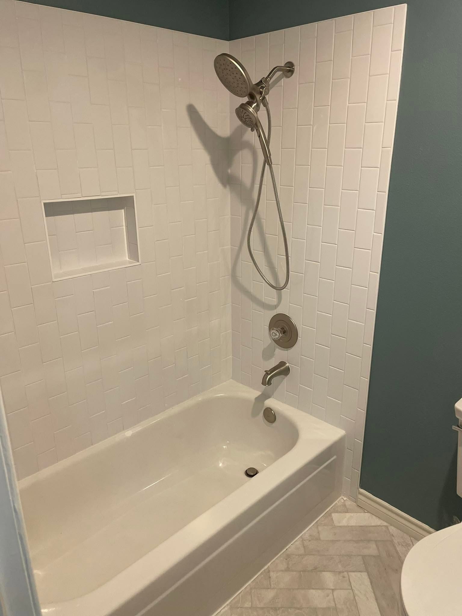 Tub-to-shower remodel with white subway tile surround, rainfall showerhead, and deep teal accent wall in a McKinney bathroom