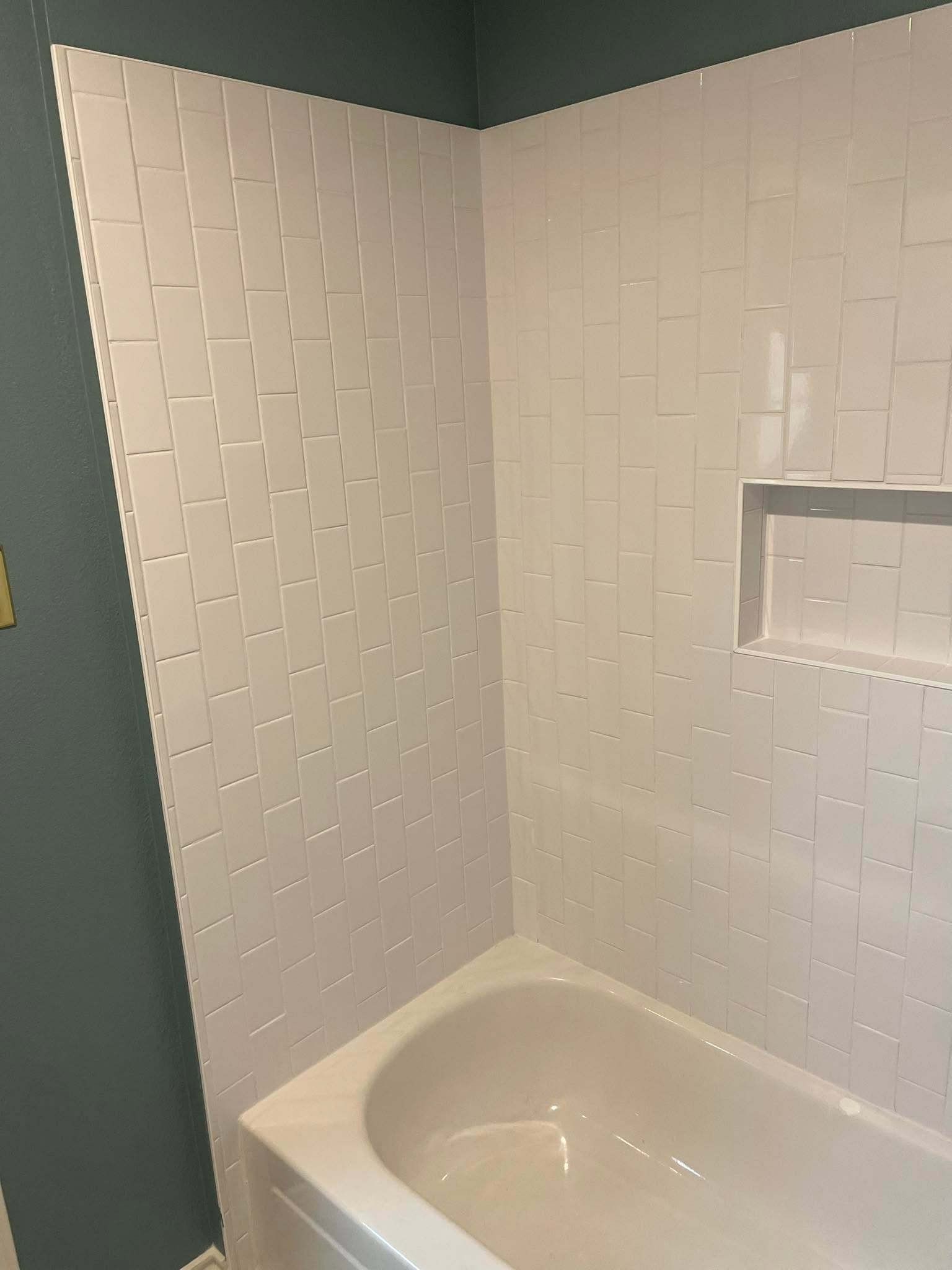 Bathtub surround in vertical white subway tile against a deep teal wall in a McKinney master bathroom