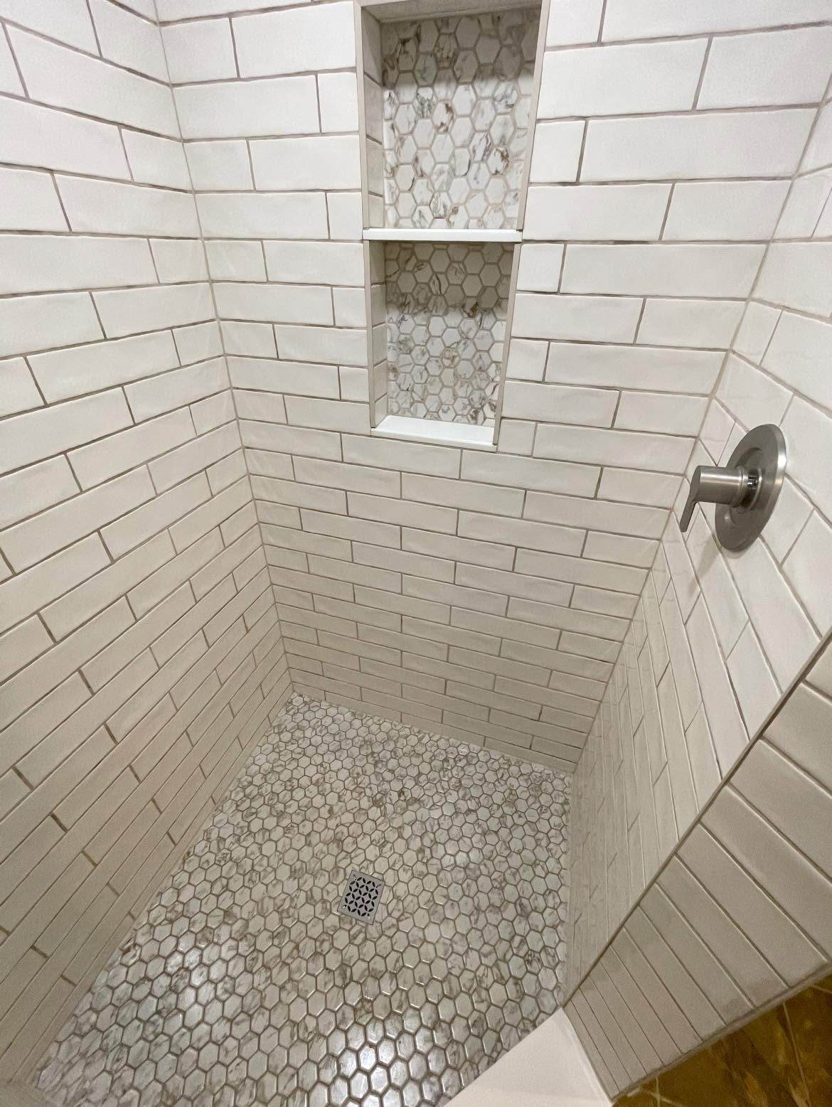 Custom walk-in shower with white subway tile walls and a marble hex-mosaic niche in a McKinney master bathroom
