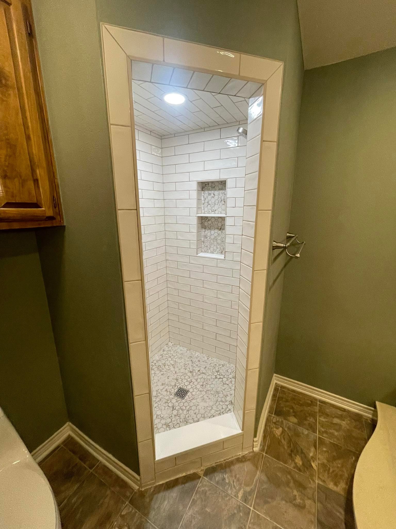 Custom subway-tile walk-in shower with mosaic floor and built-in niche, sage-painted bathroom in McKinney
