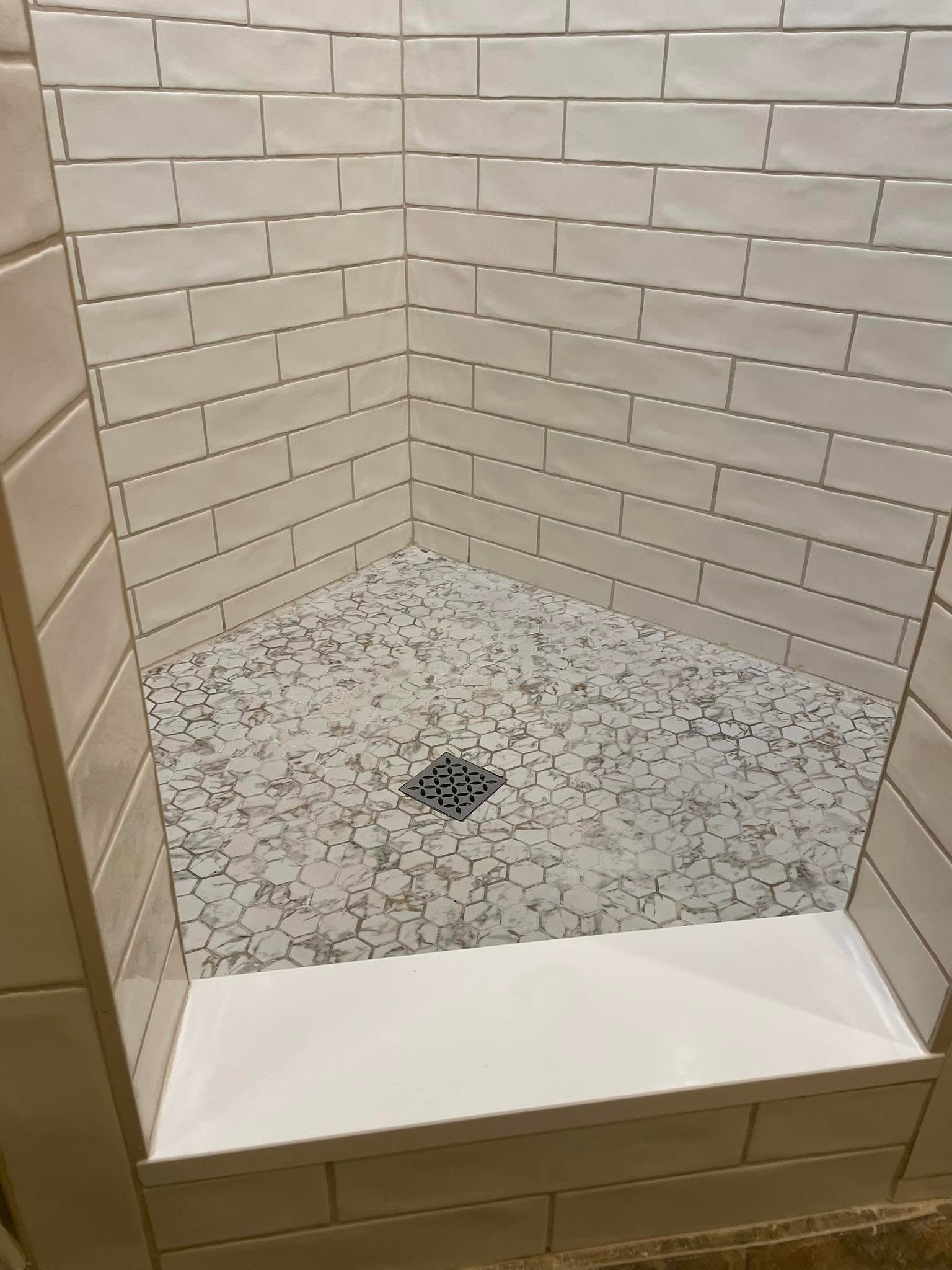 Walk-in shower with white subway tile, marble hex mosaic floor, and built-in bench by Andrades GC in McKinney, TX