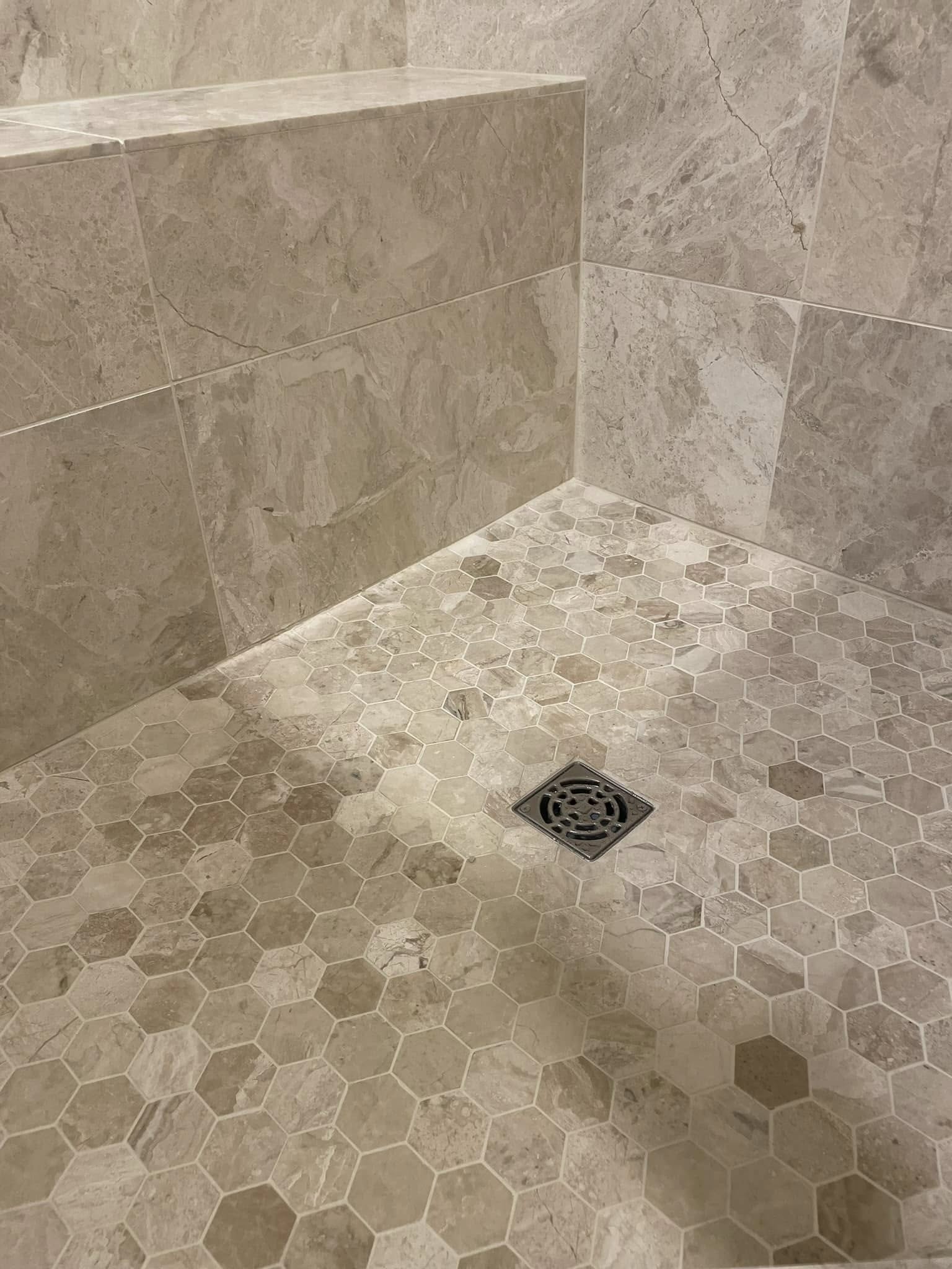 Travertine hexagon-mosaic shower floor with curb bench detail, McKinney bathroom remodel